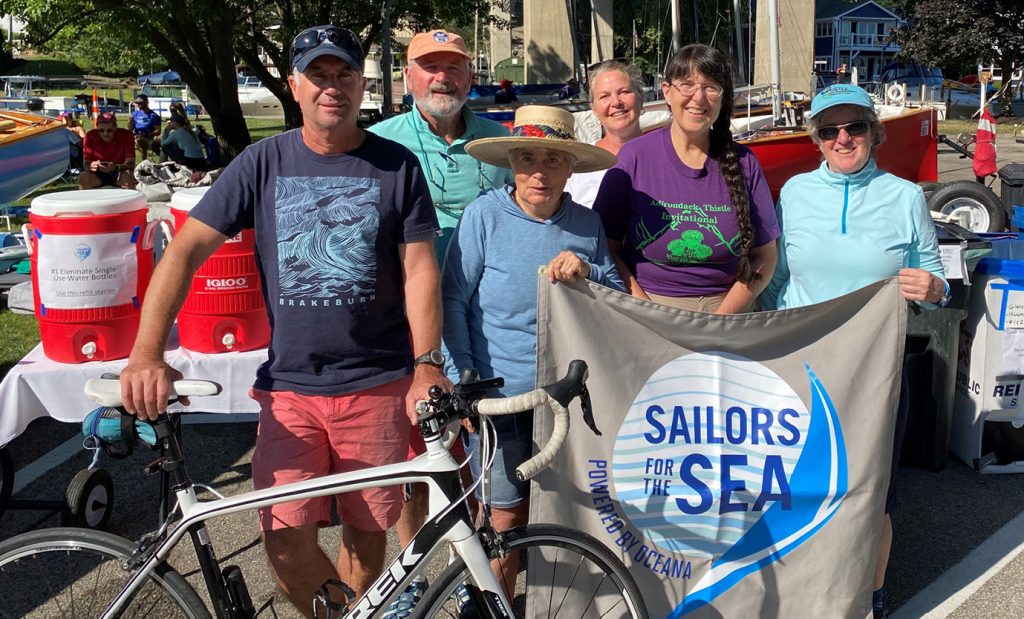 Several members of the Thistle Clean Class Initiative holding up a Sailors for the Sea flag